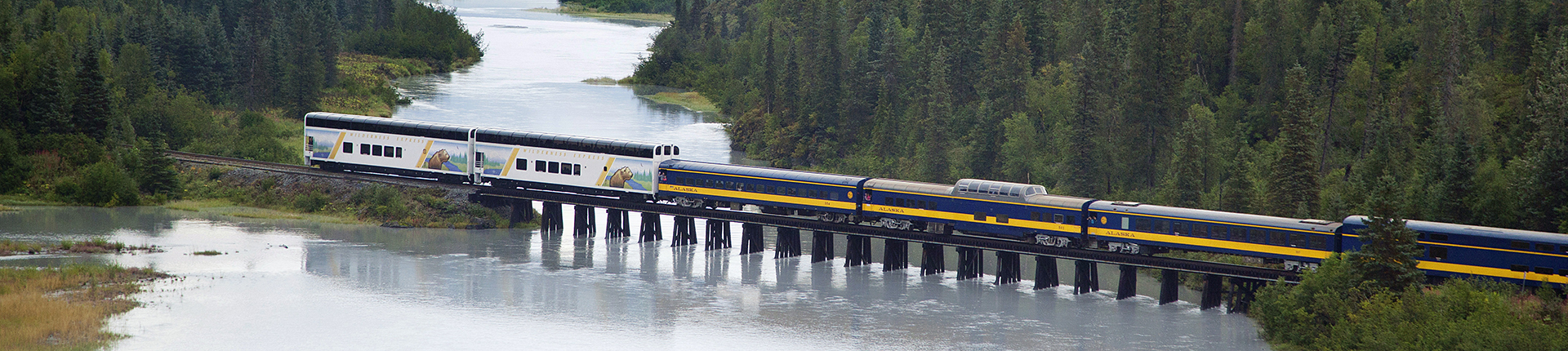 Alaska Wilderness Express railcars crossing a bridge over water