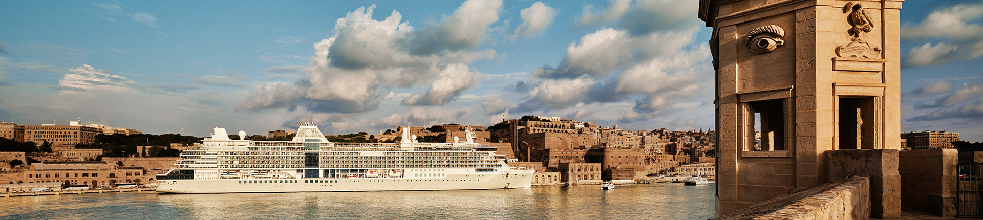 Silver Ray cruise ship docked at a port in Malta with a fortress wall in the foreground